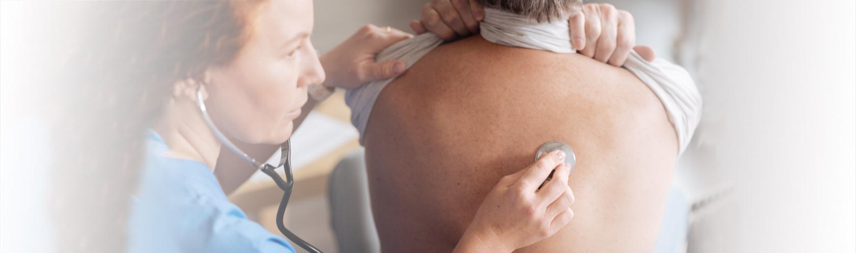 Pielęgniarka osłuchuje plecy badanego mężczyzny