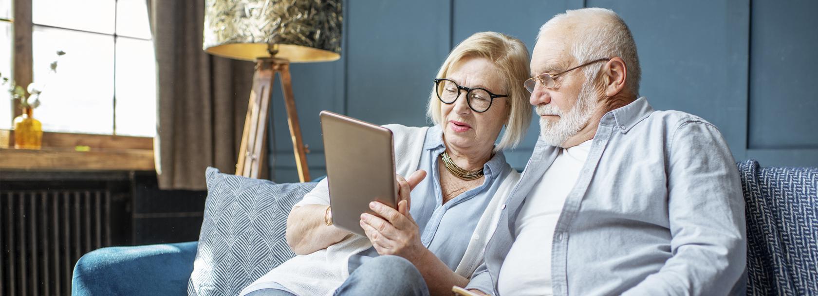 Starsza para na kanapie patrzy na tablet