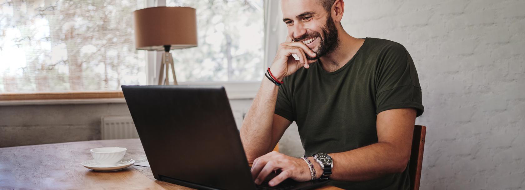 Uśmiechnięty trzydziestolatek przed komputerem