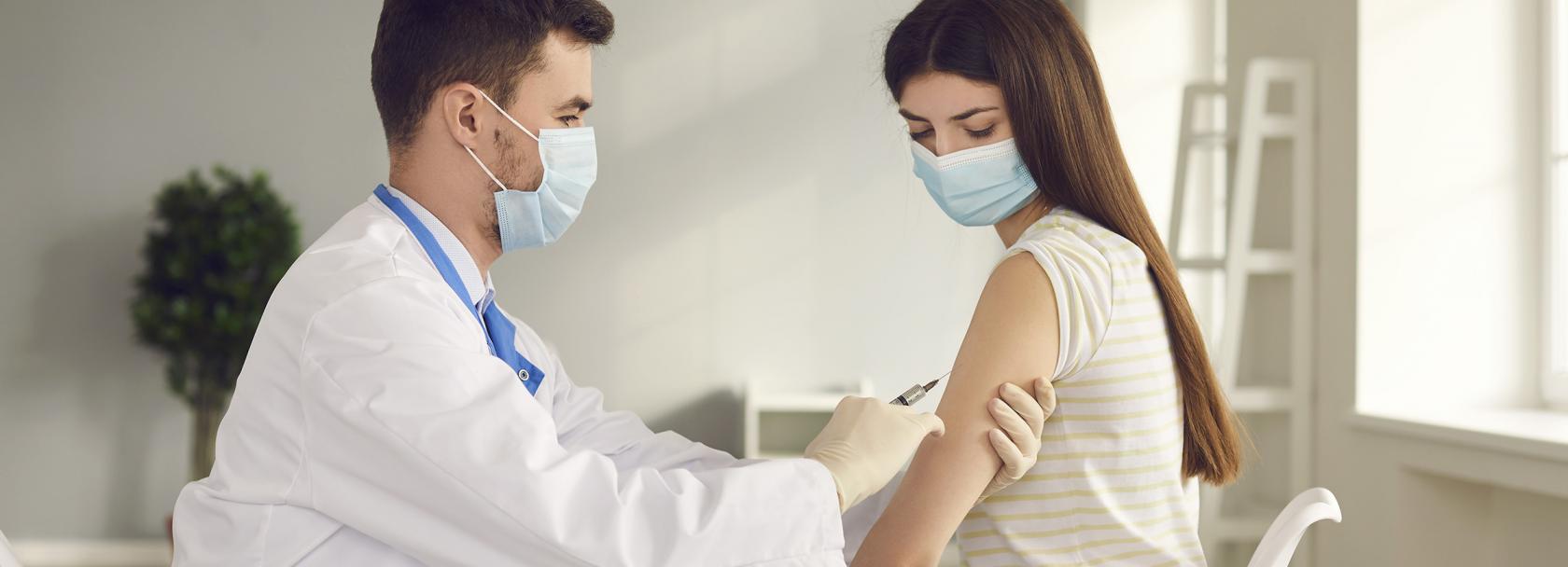 Młoda kobieta  w maseczce otrzymuje szczepionkę