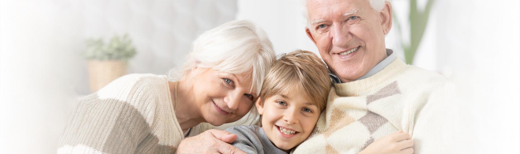 Przytuleni od lewej babcia, wnuczek, dziadek. Siedzą, patrzą na wprost.