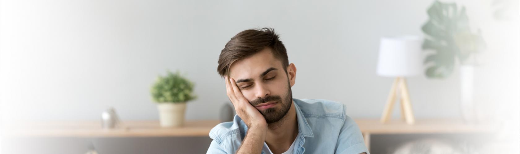 Mężczyczna przed laptopem, głowa podparta na dłoni.