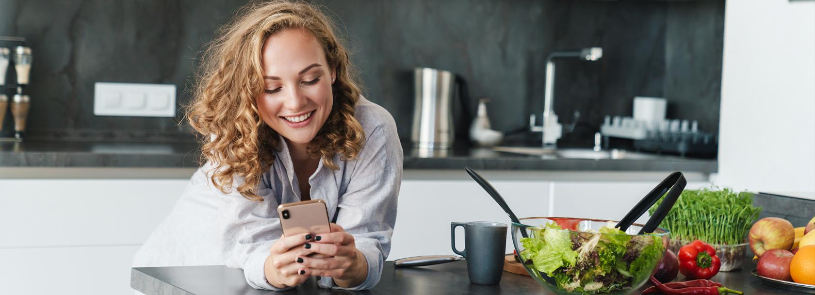 Kobieta w kuchni patrzy na telefon