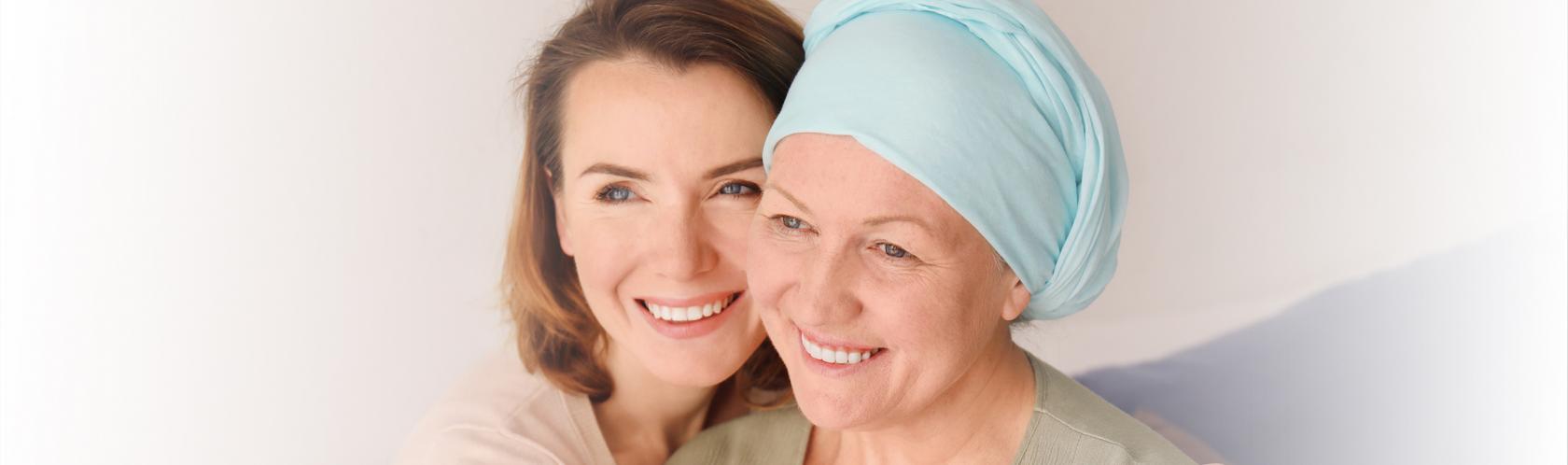 Młodsza kobieta obejmuje starszą, które głowa jest owinięta chustą