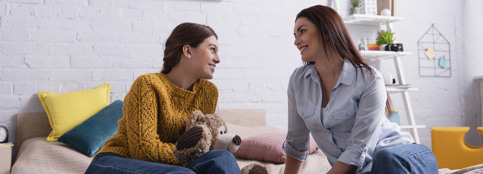 Matka z nastoletnią córką rozmawiają siedząc na tapczanie