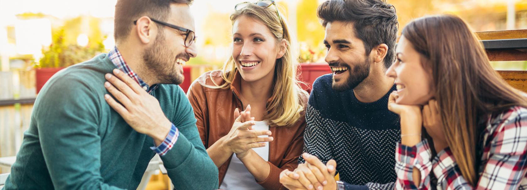 Grupa młodzieży bez maseczek rozmawia przy stole