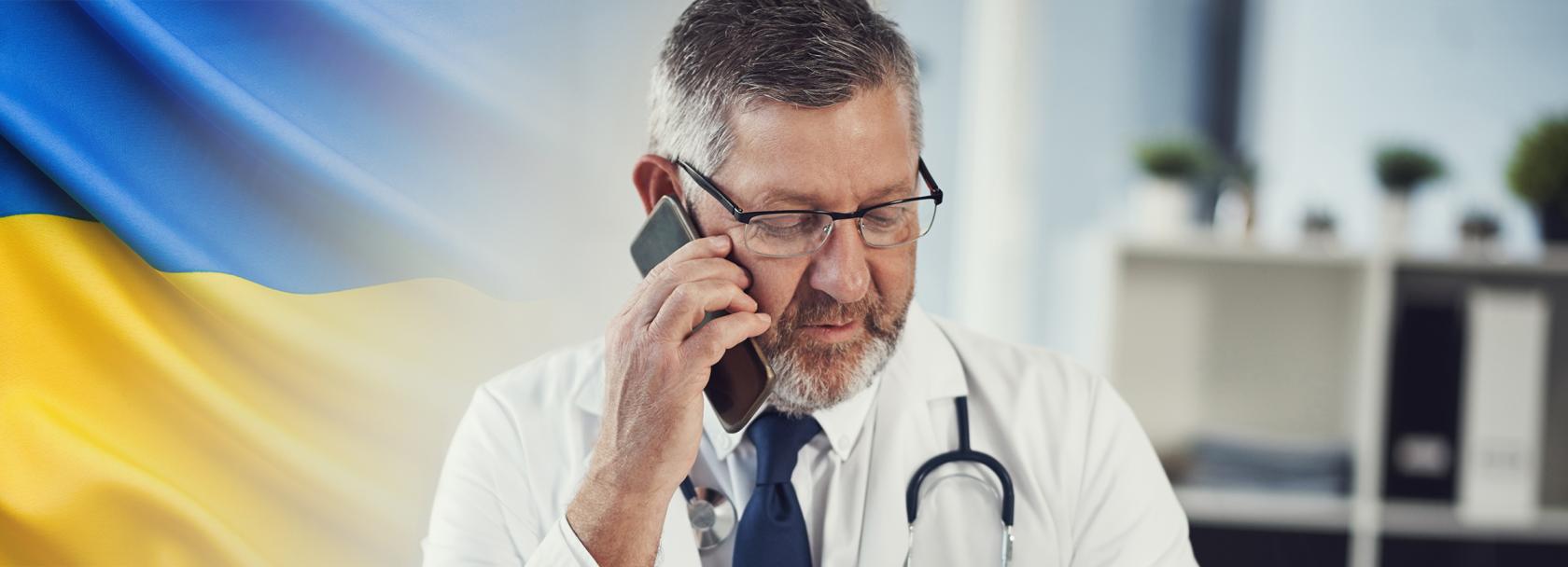Lekarz rozmawiający przez telefon, z lewej strony ukraińska flaga