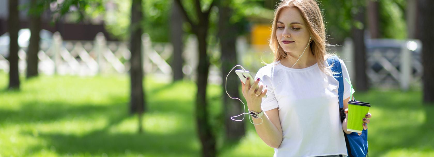 Kobieta na spacerze patrzy na komórkę