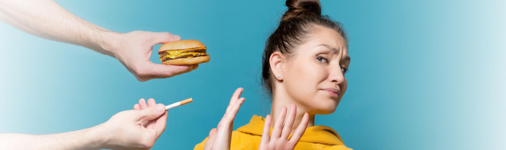 Kobieta odwraca głowę i krzyżuje ręce na znak protestu przed papierosem, fast foodem i alkoholem.