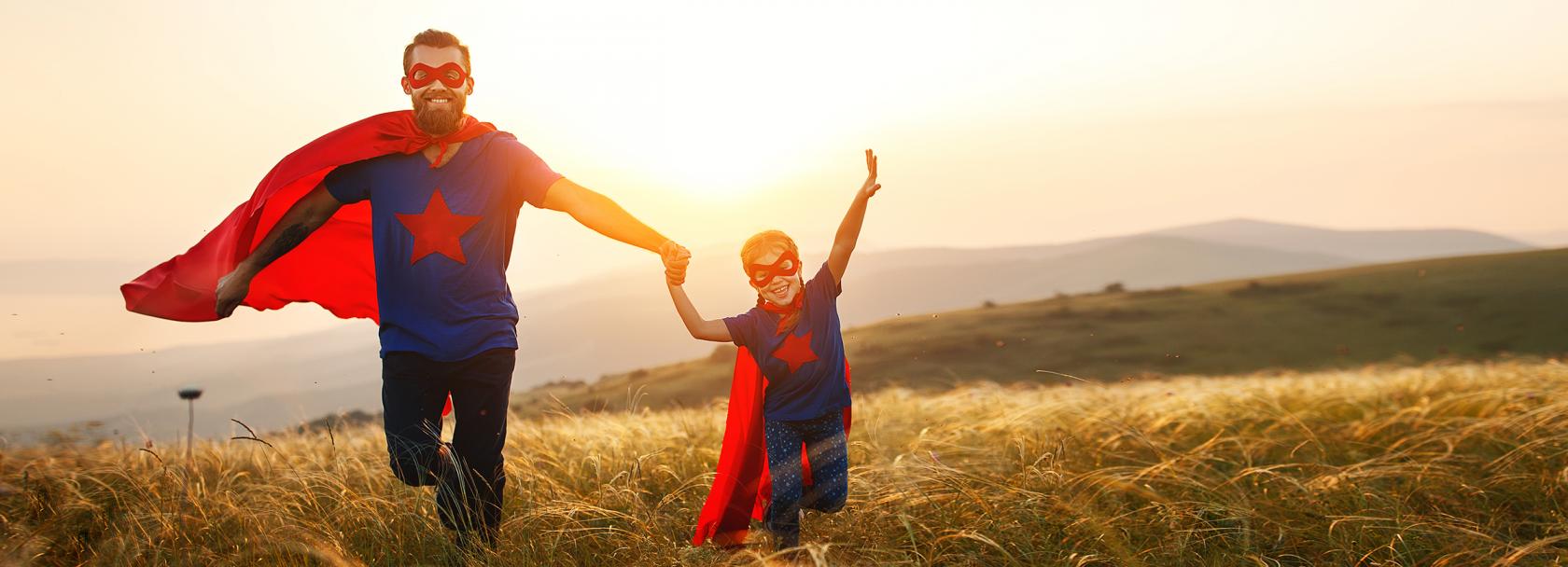 ojciec i syn na łące w czerwonych pelerynach