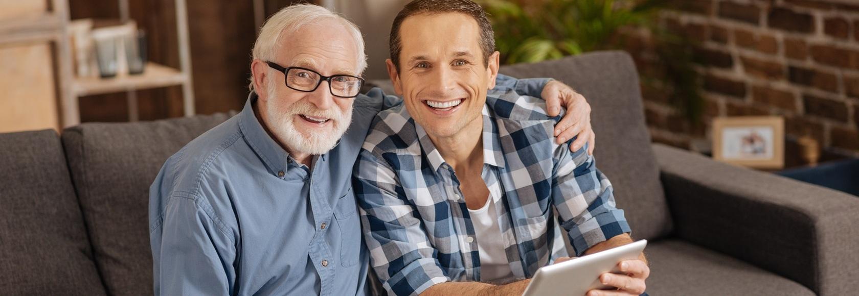 Dwaj mężczyźni siedzą na kanapie. Jeden jest starszy, a drugi młody.