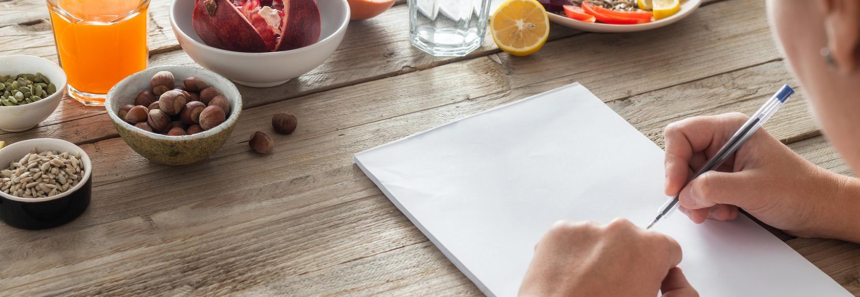 ręce z kartką i długopisem na stole z produktami żywieniowymi