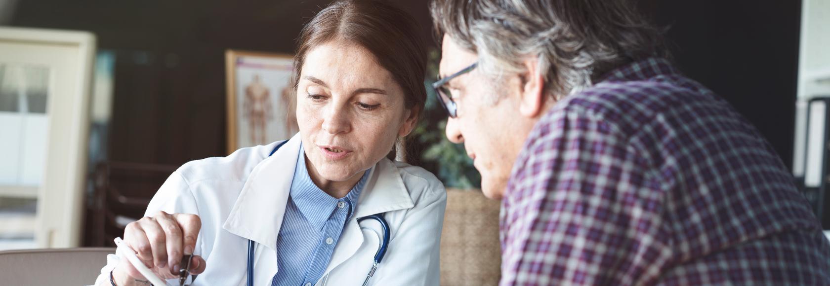 Lekarka omawia wyniki badań z pacjentem, który jest mężczyzna w 50 roku życia.