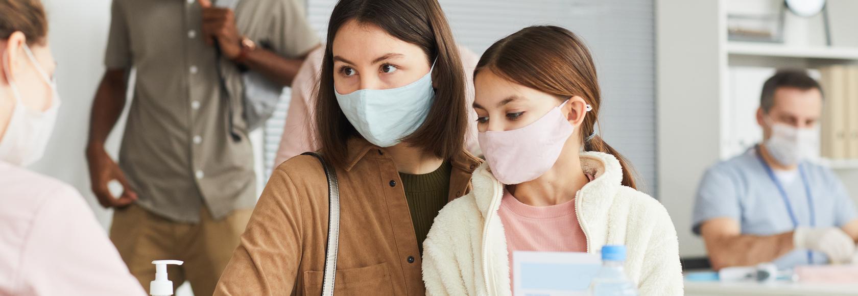 Przychodznia, matka z córką na kolanach zapisuje się na wizytę do specjalisty.