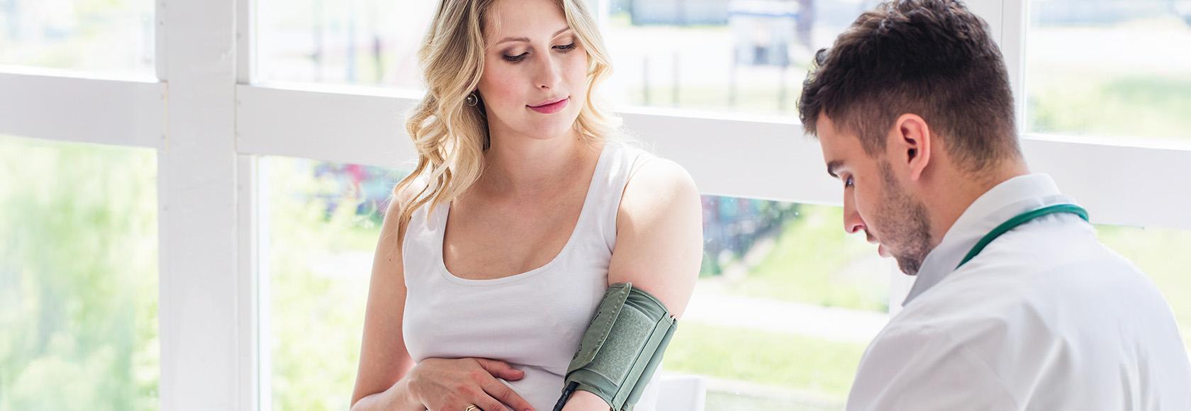 lekarz bada cisnienie ciężarnej kobiecie