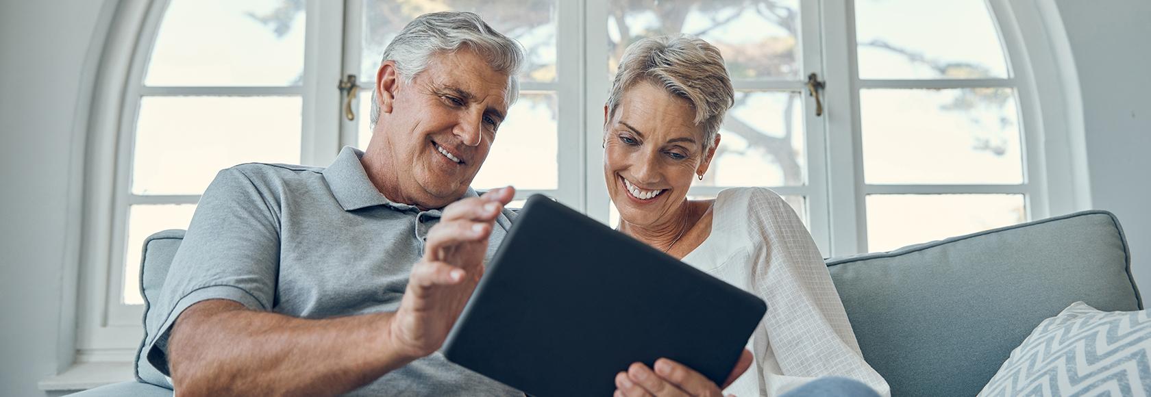 Mężczyzna i kobieta w średnim wieku patrzą w tablet, który trzyma mężczyzna