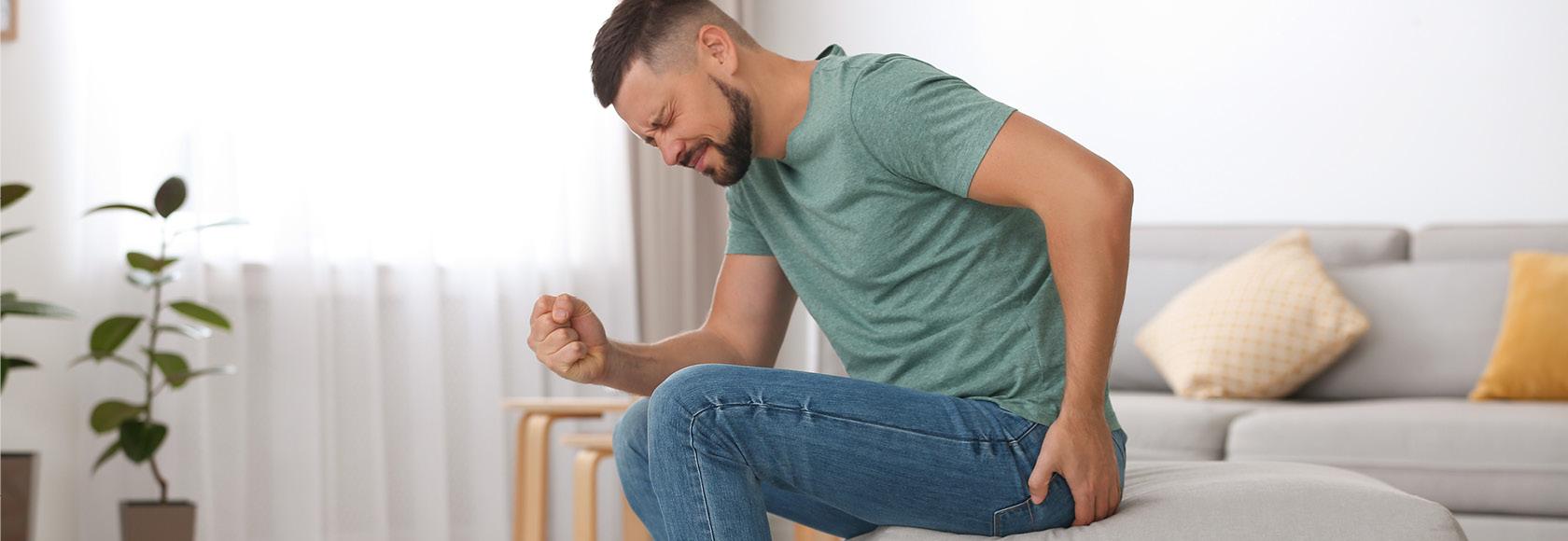 mężczyzna podnosi się chwytając się za pośladek