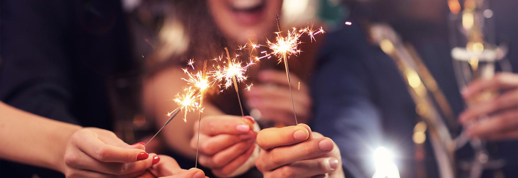 Palące się sztuczne ognie trzymane w dłoniach.