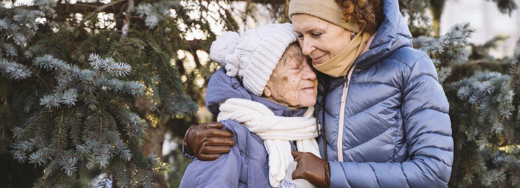 50latka przytula starszą panią, obie w kurtkach i czapkach