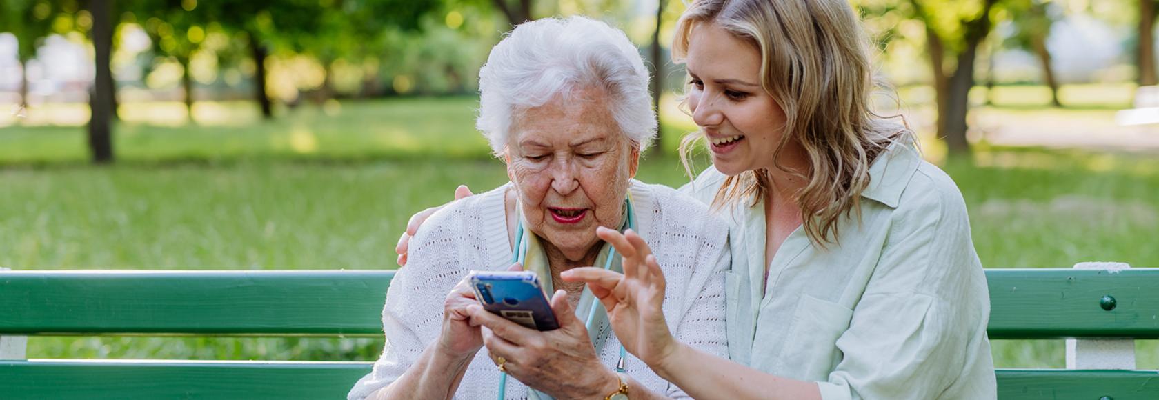 Mloda dziewczyna pokazuje seniorce coś na komórce