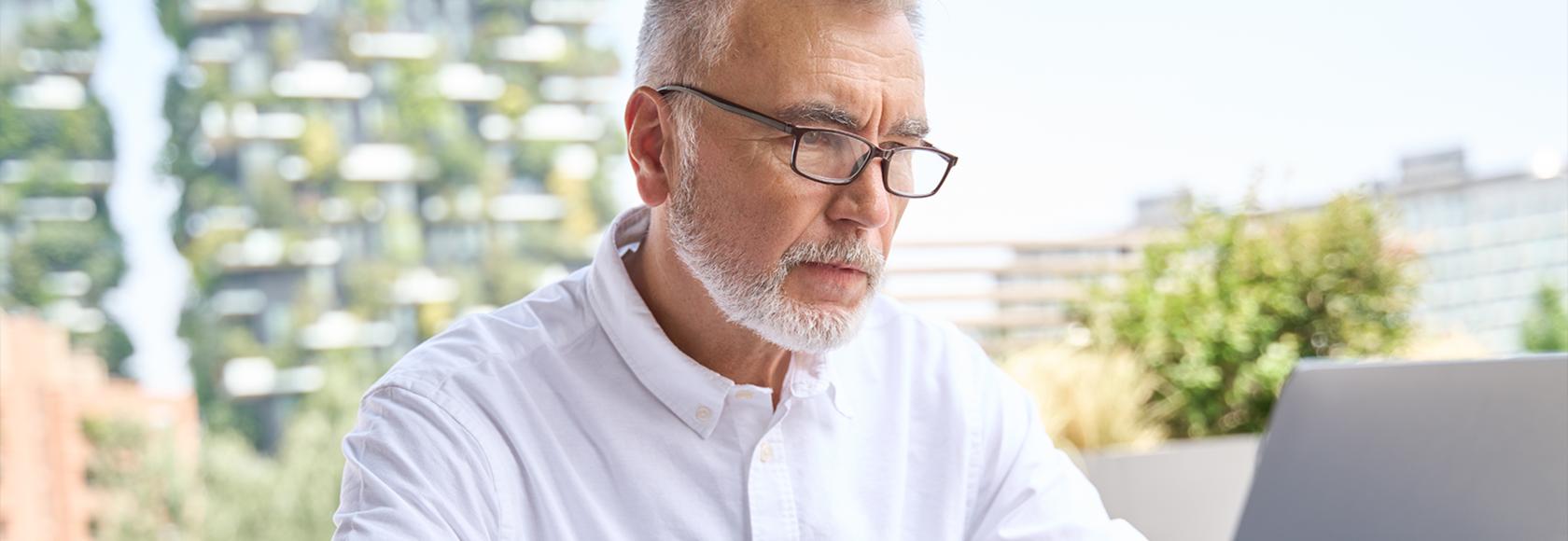 mężczyzna z brodą w białej koszuli przy komputerze