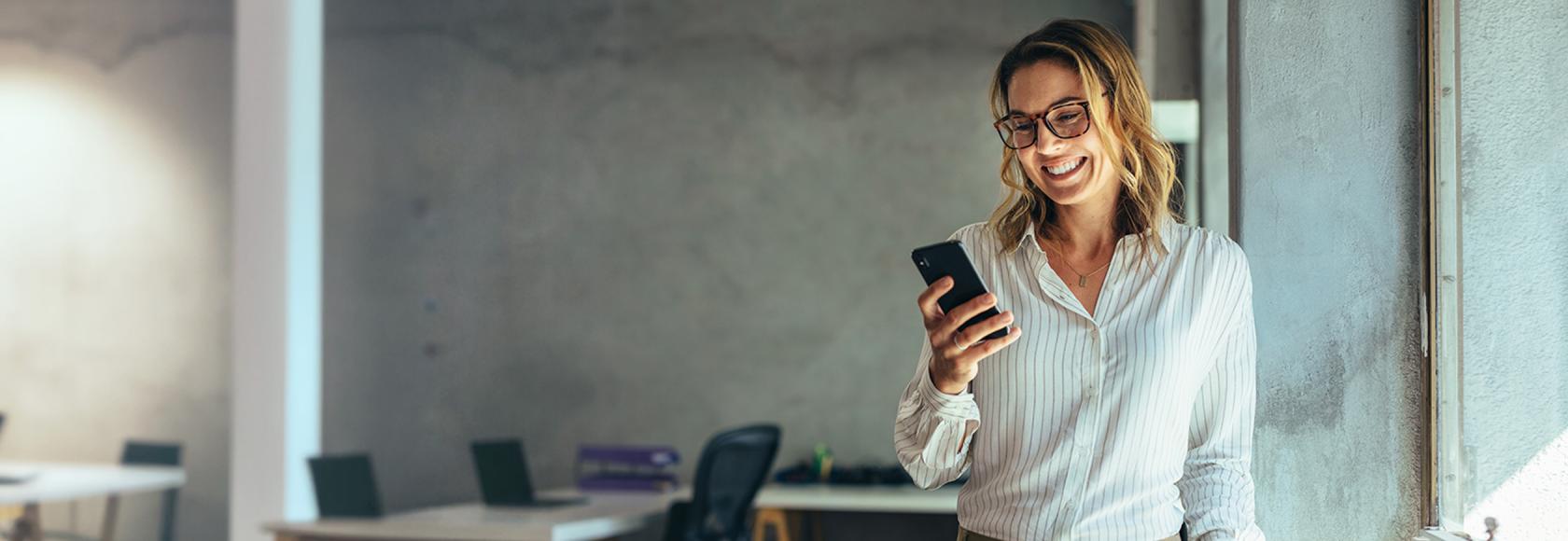 Dzewczyna w bialej  bluzce z komórką , w tle  biuro