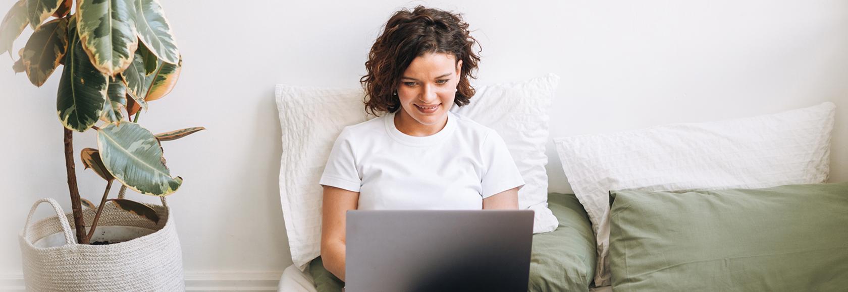 Kobieta siedzaca na łozku z laptopem