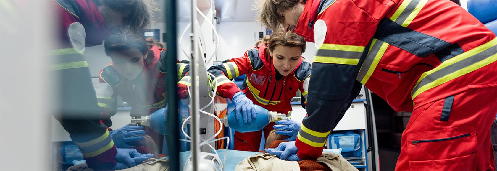 dwoje ratownikow w karetce robi masaż serca