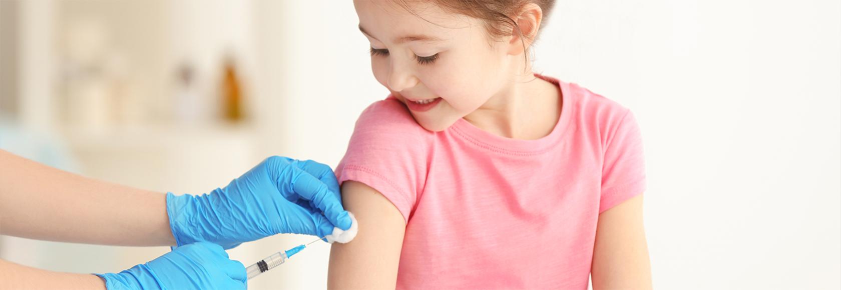 Widać ręce pielęgniarki i szczepioną kilkuletnią dziewczynke