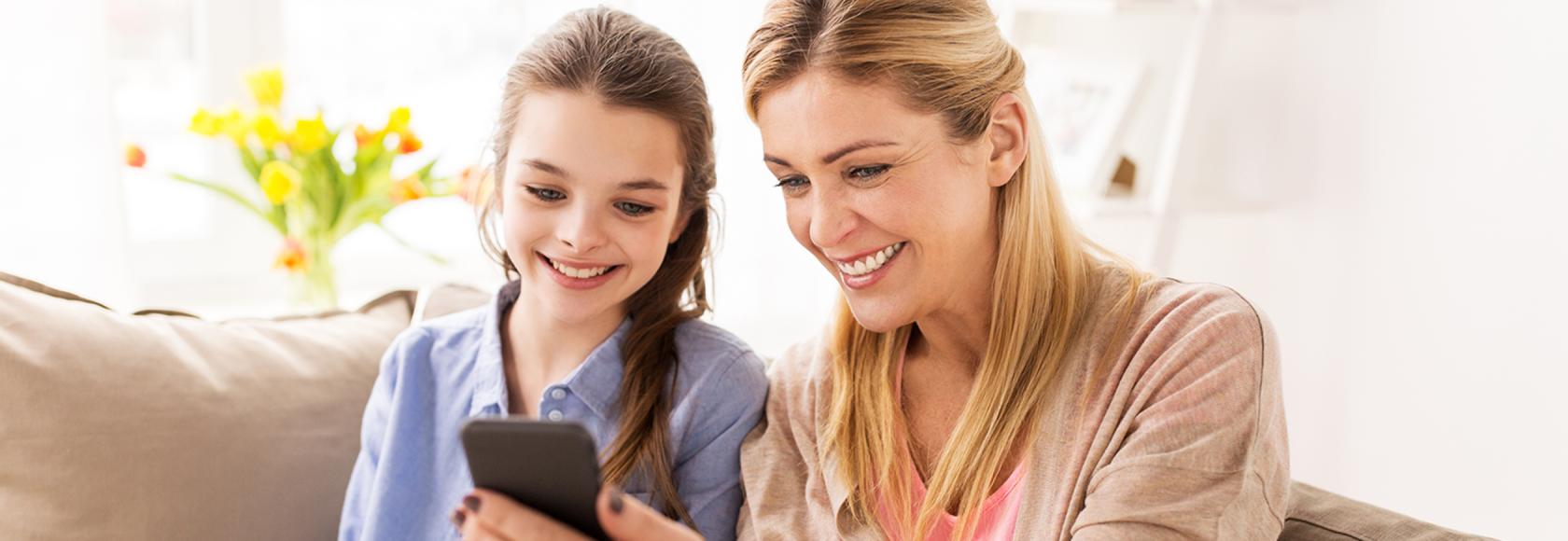 matka z komórką w ręku z córka na kanapie