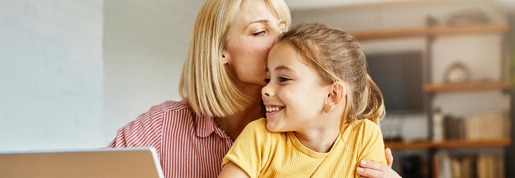 Matka czule przytula dziecko przy kompie