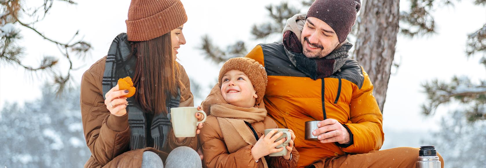 rodzinka w zimowym lesie pije herbatę z termosu