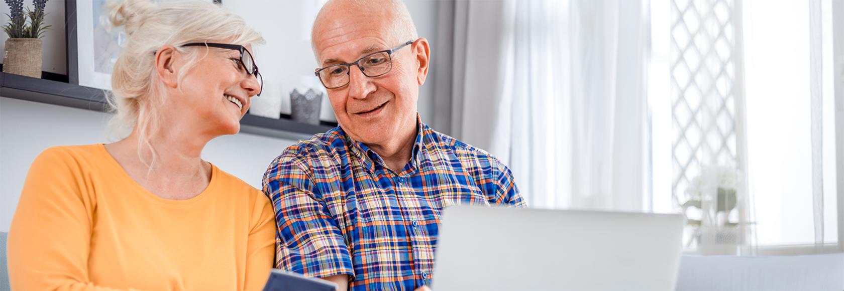 starsza pani z komórką, starszy an z laptopem, smieją się