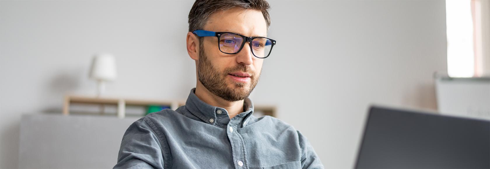 Młody mężczyzna w okularach przed laptopem