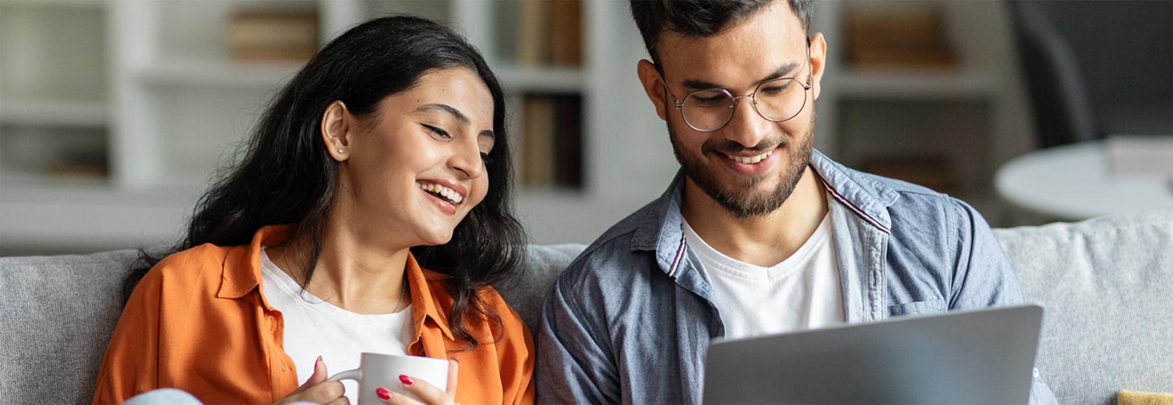 Para na kanapie, młodzi, zadowoleni, chlopak z laptopem