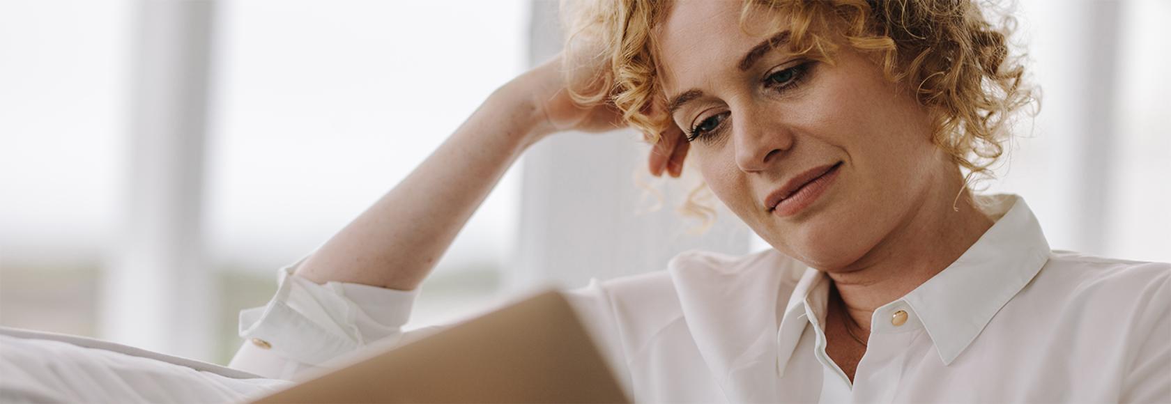 kobieta z laptopem na kolanach, w białej bluzce