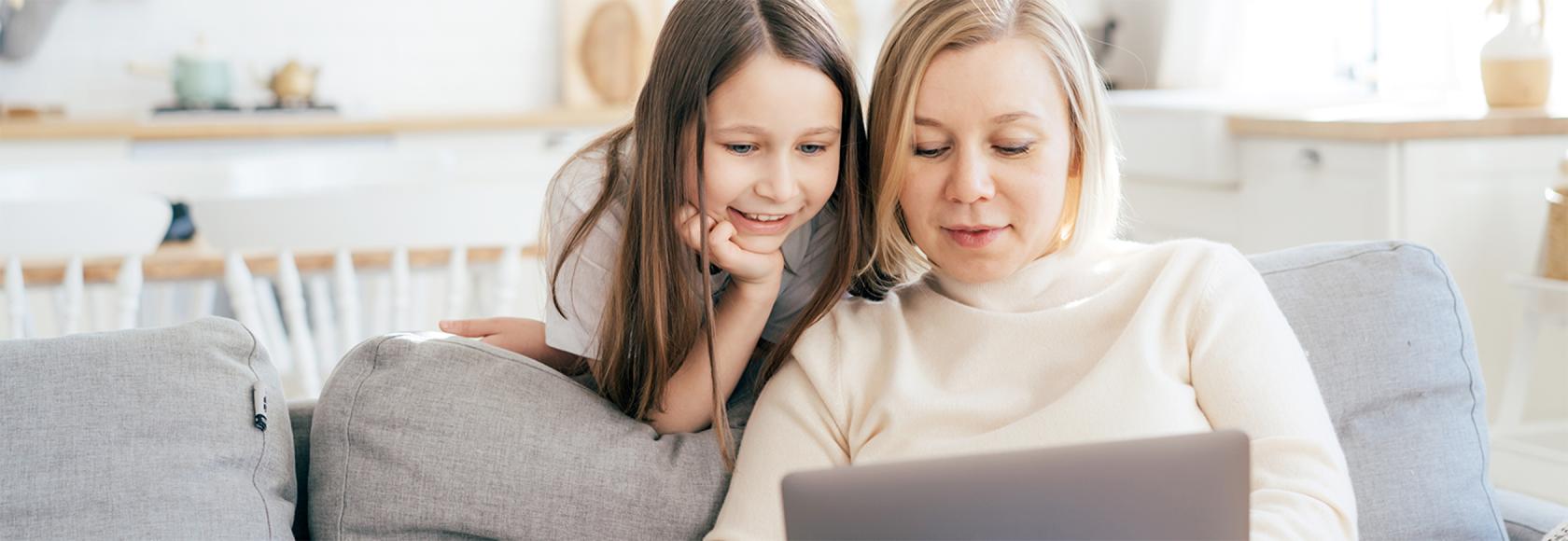 córka zagląda przez ramię matce czytającej informację w komputerze