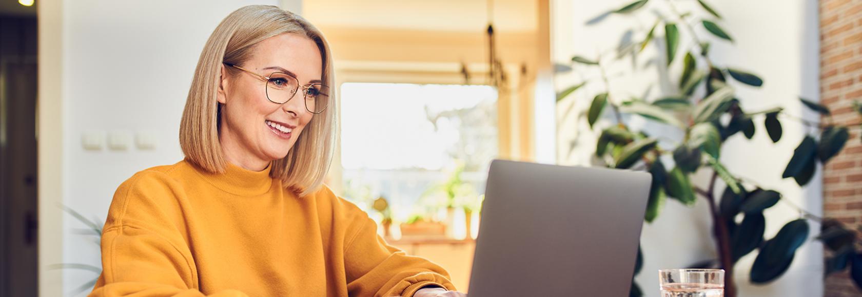 Kobieta w żołtej bluzie przed komputerem