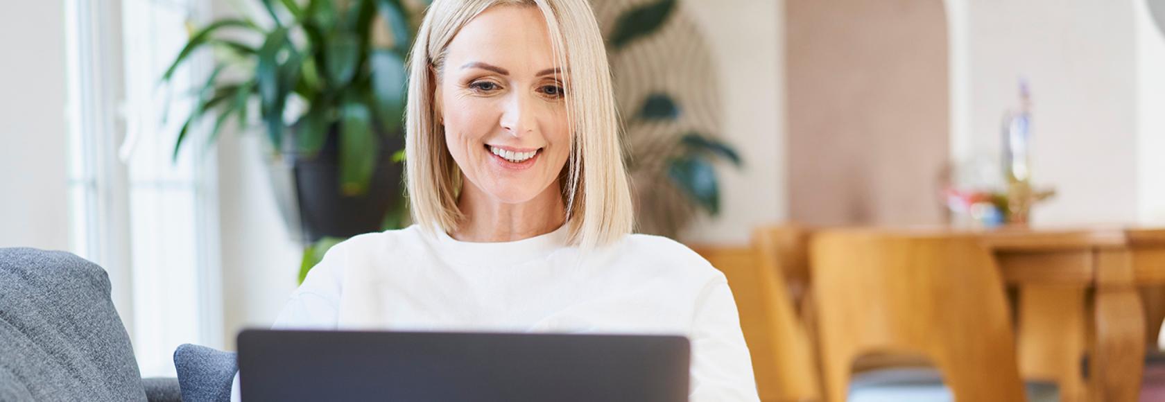 Kobieta w białym t-shircie z laptopem na kanapie