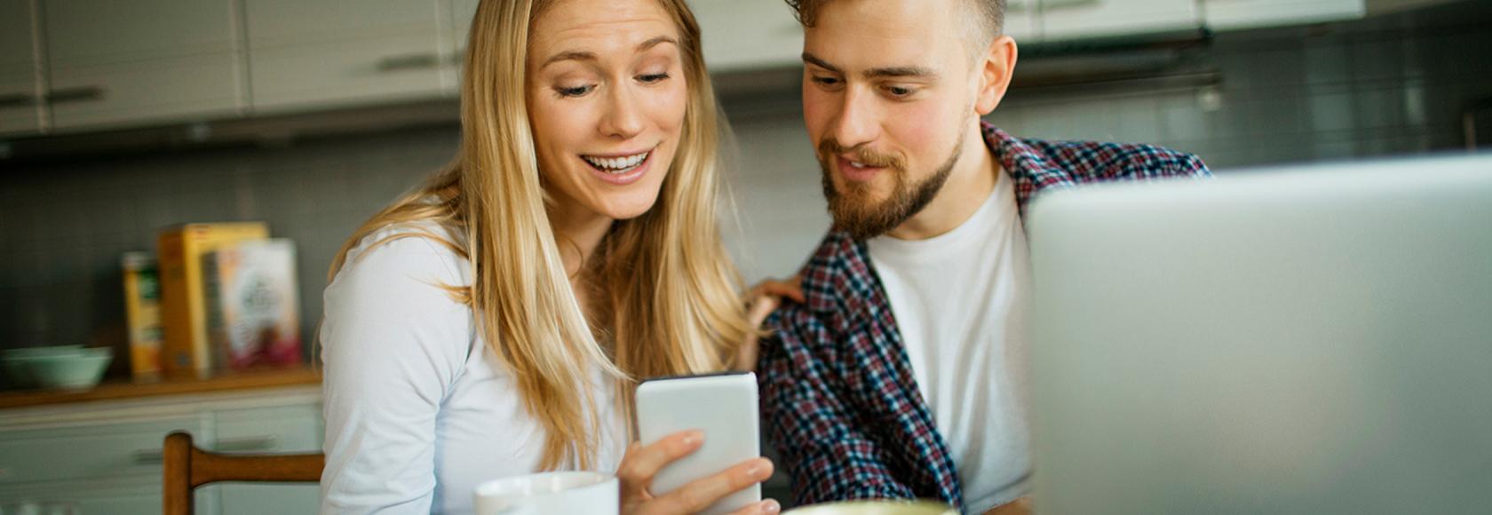 po sniadaniu w kuchni, cz\lopak przed laptopem patrzy na dziewczynę z komórką