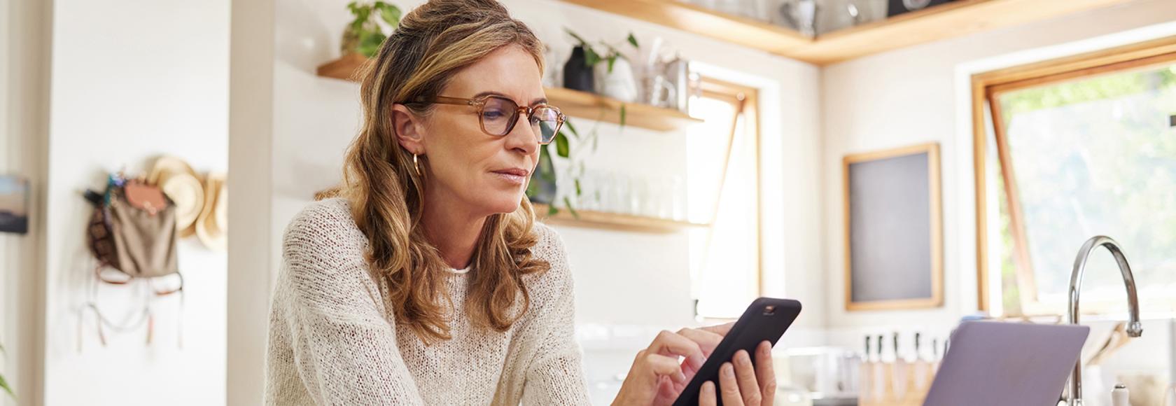 Pani patrz na telefon, a przed nią komputer. Jest poważna