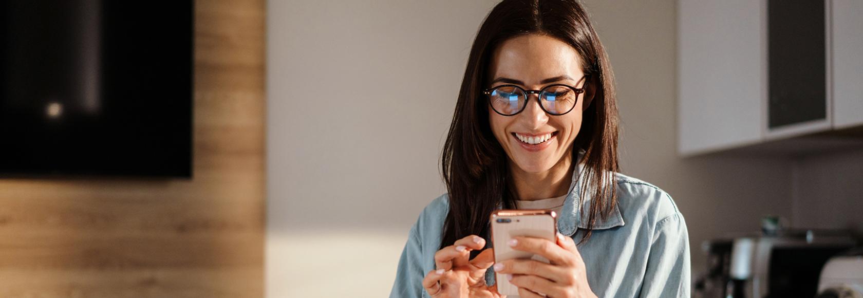 młoda szatynka z telefonem w swojej kuchni