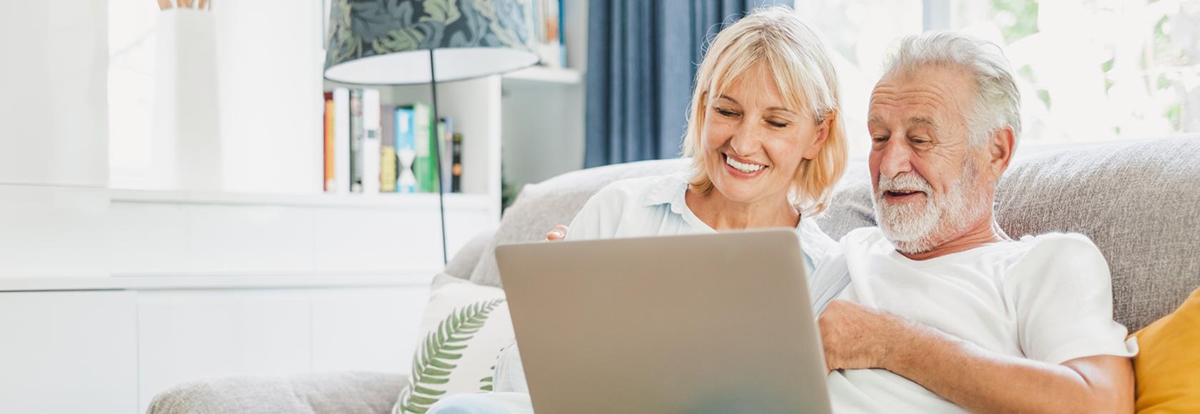 para w średnim wieku na kanapie z komputerem