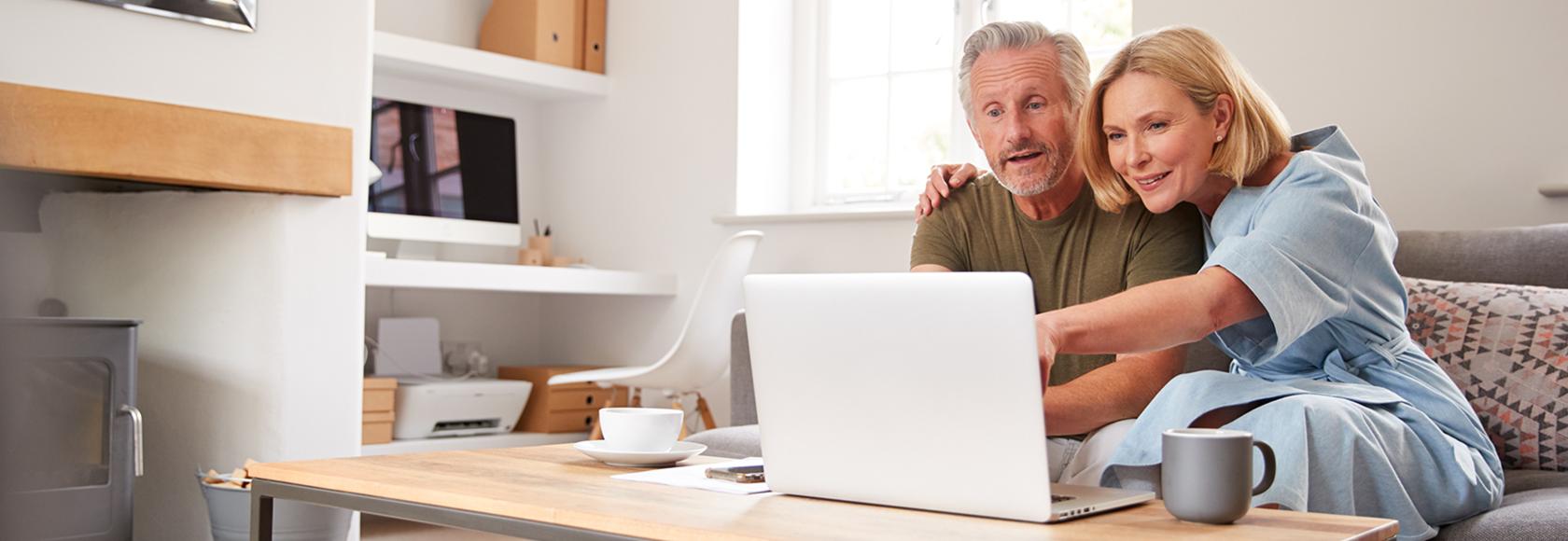 Para na kanapie patrzy w komputer