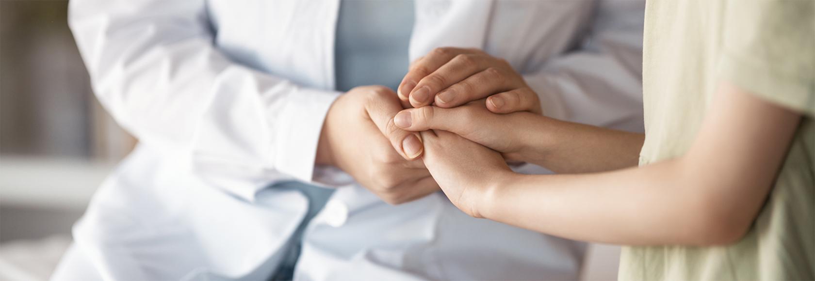 Lekarz trzyma pacjenta za rece