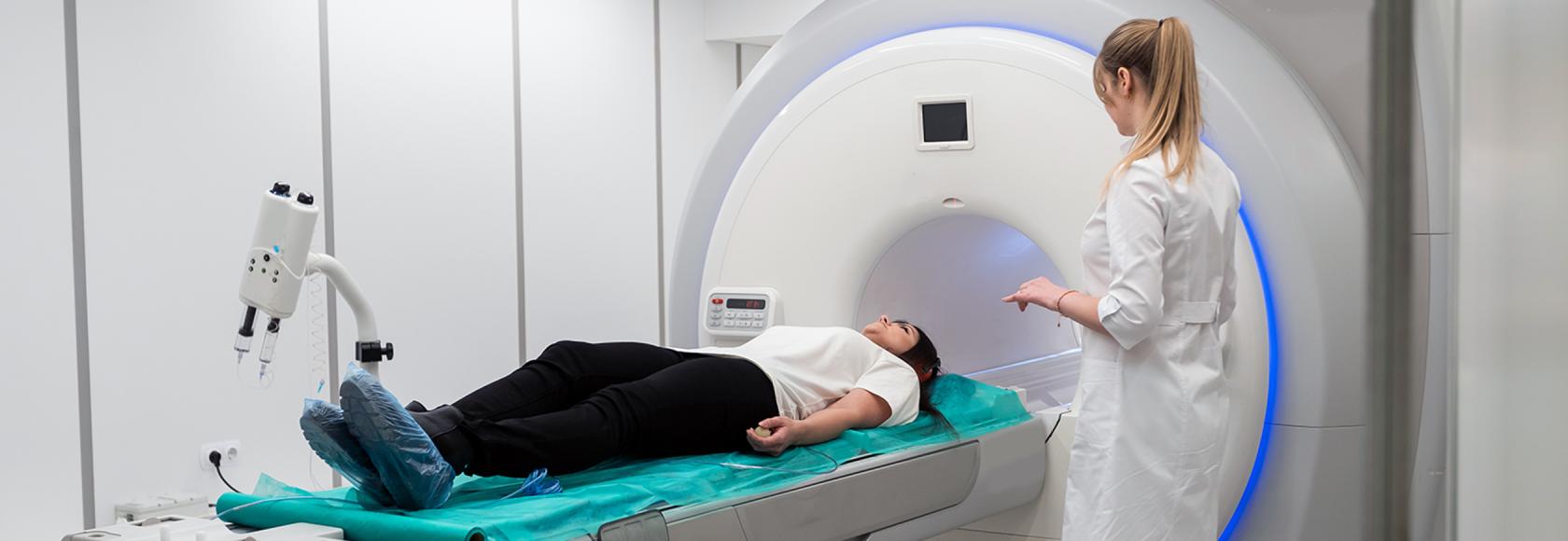 osoba wjeżdża do tuby obok stoi pielegniarka