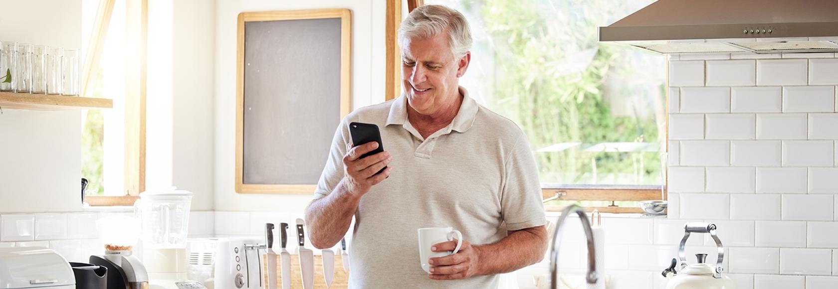 50latek w kuchni patrzy na telefon