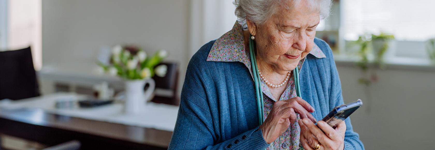 Starsza pani wybiera coś na komorce