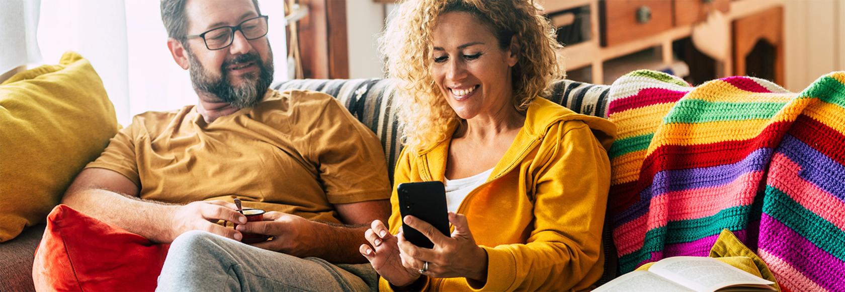 para na kanapie, uśmiechnięci, ona z telefonem