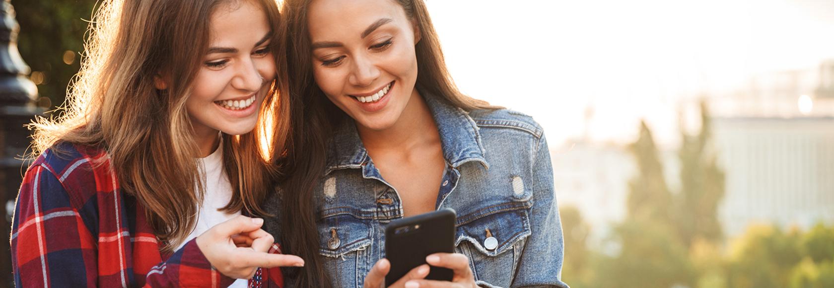 kobieta we flanelowej koszuli pokazuje drgiej coś na jej komórce